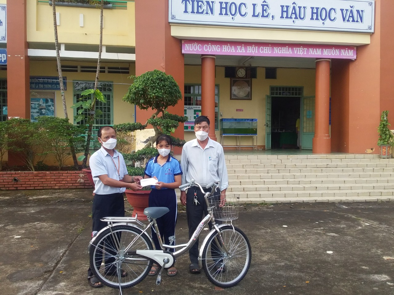 Ông Hoàng A Pẩu (bên trái) tặng xe đạp cho em học sinh đồng bào dân tộc thiểu số tại trường Tiểu học Nguyễn Huệ.jpg